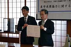 協定書を掲げる古山学長（右）と森屋松吉京都北都信用金庫理事長