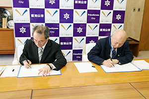 協定書に署名する古山学長・松山正治福知山市長
