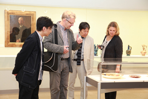 美術工芸資料館平芳幸浩准教授（左）から展示品の説明を受けるDreysse 氏（左から二人目）