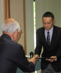 同窓会会長より採択決定通知書を授与される髙橋准教授