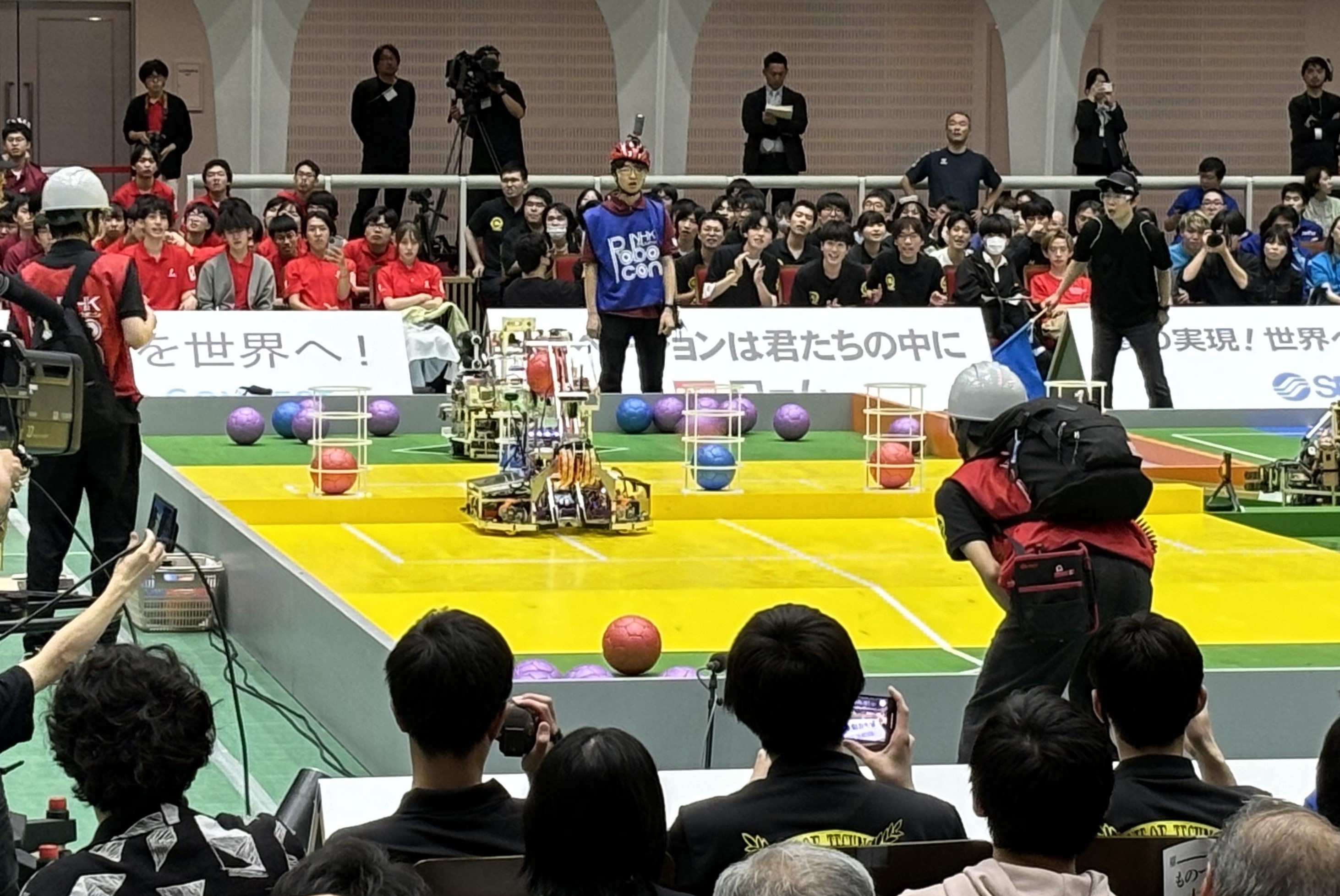 もみ（赤いボール）を筒に入れようとする自動ロボット